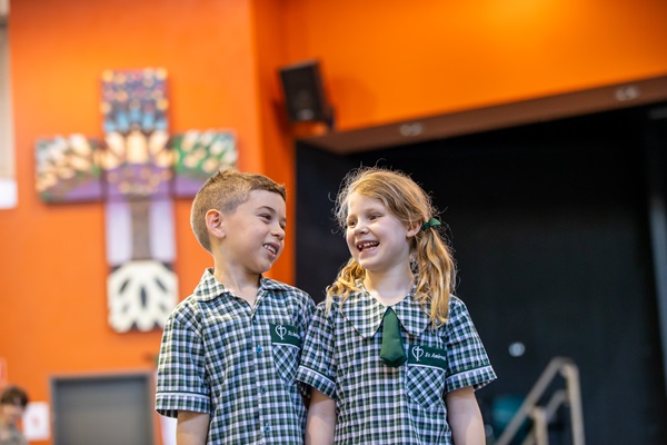 Students standing together in the school hall wearing St Ambrose’s Primary School uniform, representing friendship, belonging and everyday school life