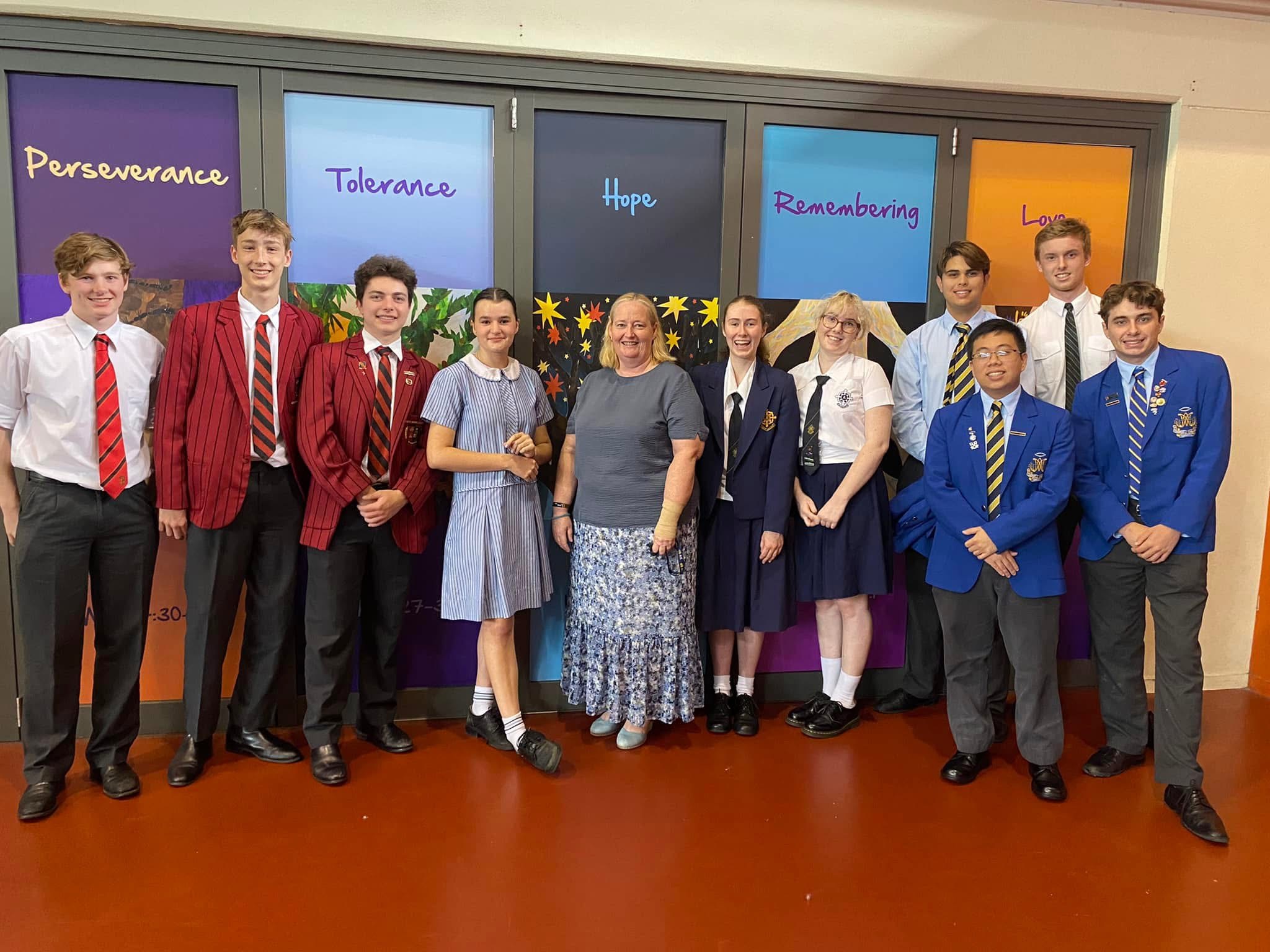 Students and staff standing together in front of a values display, highlighting partnership, shared values and community connection within the school community