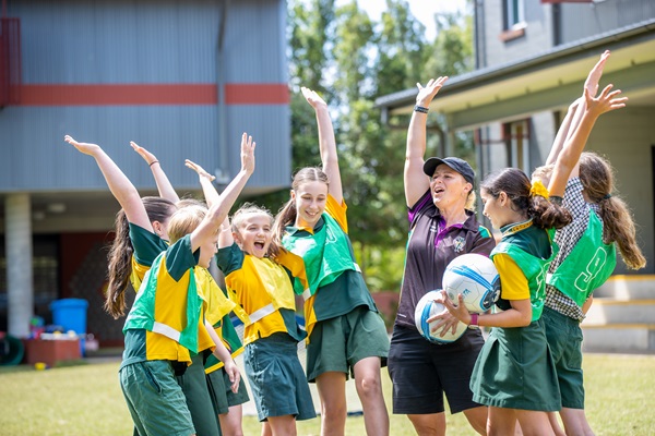 Students and a staff member celebrating together during an outdoor sport activity, highlighting teamwork, physical activity and positive participation in school life