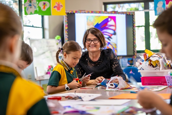 Teacher working alongside students during a creative classroom activity, highlighting hands‑on learning, creativity and supportive guidance in the learning environment