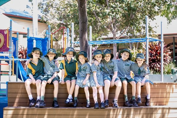 Students sitting together on outdoor seating near the playground, highlighting friendship, belonging and positive relationships within the primary school environment